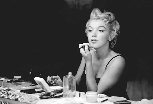 Marilyn_Monroe_putting_on_her_makeup_with_makeup_and_perfume_in_front_of_her_.jpg
